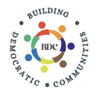 Logo. The words Building Democratic Communities circling a smaller circle of rainbow colors with BDC in the middle