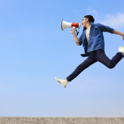 Excited young man jumping in air with megaphone to imply getting the word out about the TAships.