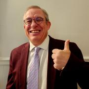 Poli Sci Department Chair, in purple suit jacket, smiling and giving thumb's up sign