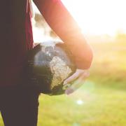 Hand holding globe in a field