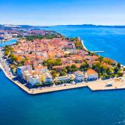Picture of dense, picturesque European village of red roof buildings clustered on a small island on a deep blue sea