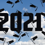 Blue sky backdrop with graduation caps high in the air with year 2021 to indicate it is the graduation for 2021