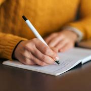 Stock Image of a individual writing in a notebook 