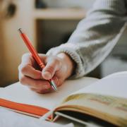 Person writing with a red pen