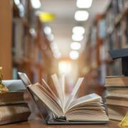 Stacks of books with a graduation cap and diploma role