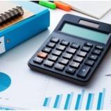 desk with calculator, notebooks, binders, pens and glasses