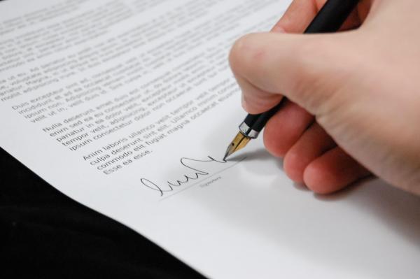 image of hand signing a piece of paper