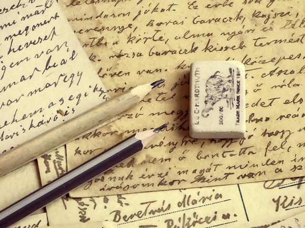 image of pencils, an eraser, and paper with cursive writing on it. 