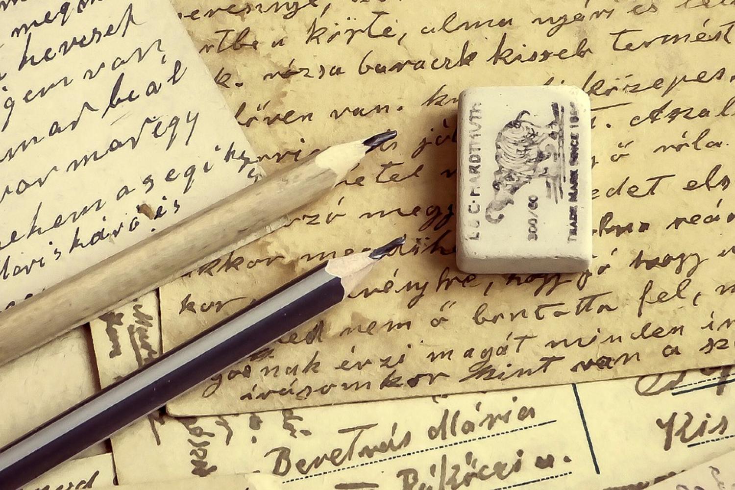 image of pencils, an eraser, and paper with cursive writing on it. 