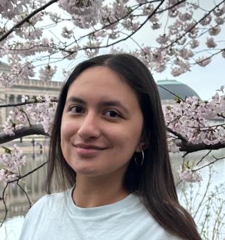 Kaylee smiling in front of a tree with white flowers