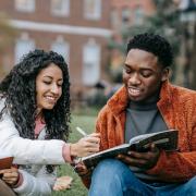 woman with curly hair pointing at a book in a man's hands